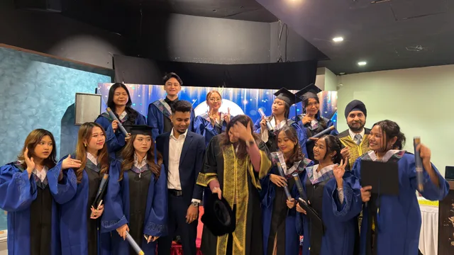 Graduates in blue gowns making cheerful gestures together