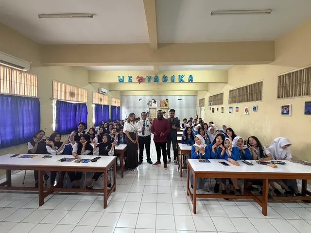Students and visitors posing together among classroom desks