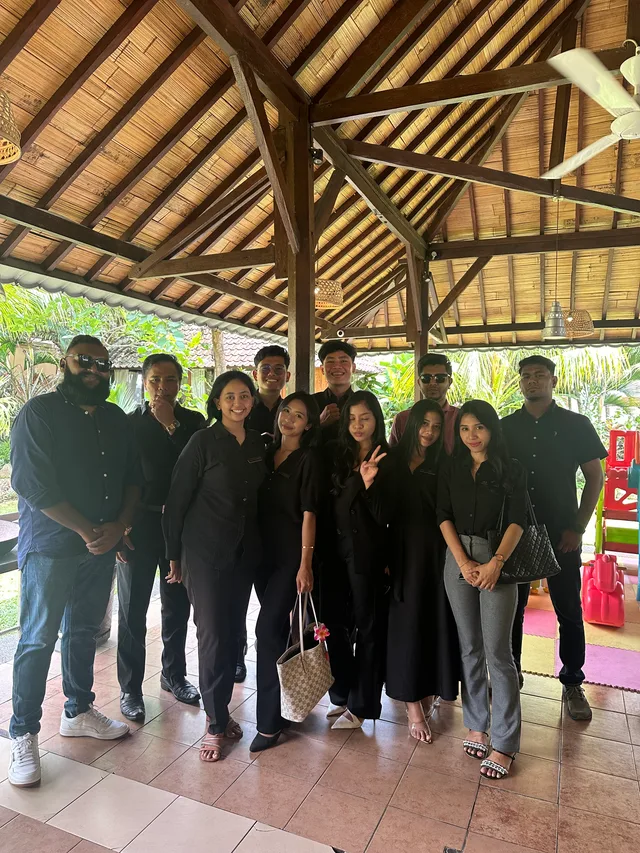 A group posing beneath an open-air timber pavilion
