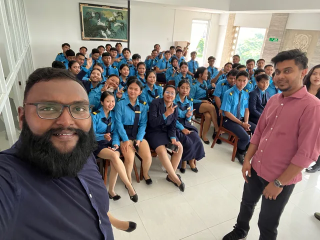A group selfie with students seated in a campus meeting room
