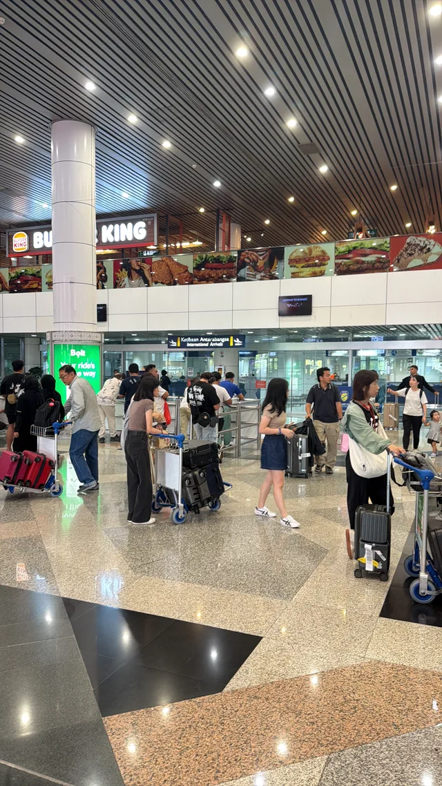 A wider view of students and luggage in the airport arrivals hall