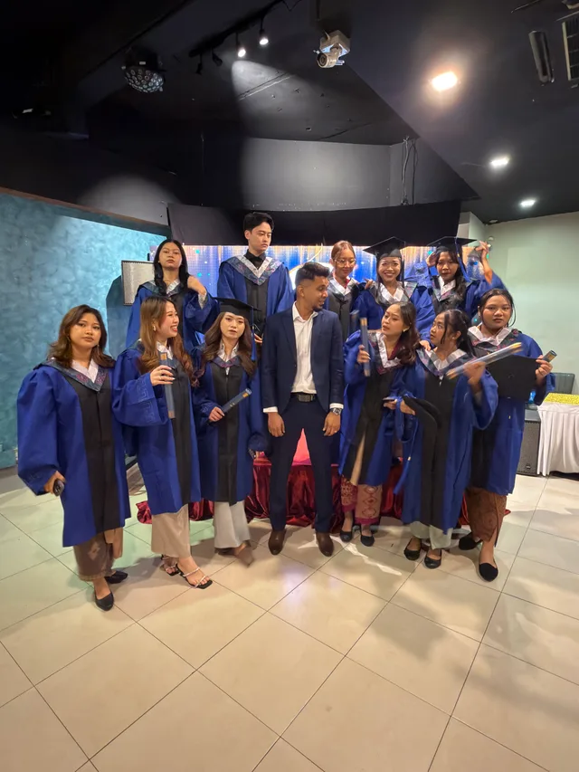 Graduates in blue gowns gathered for a group photograph